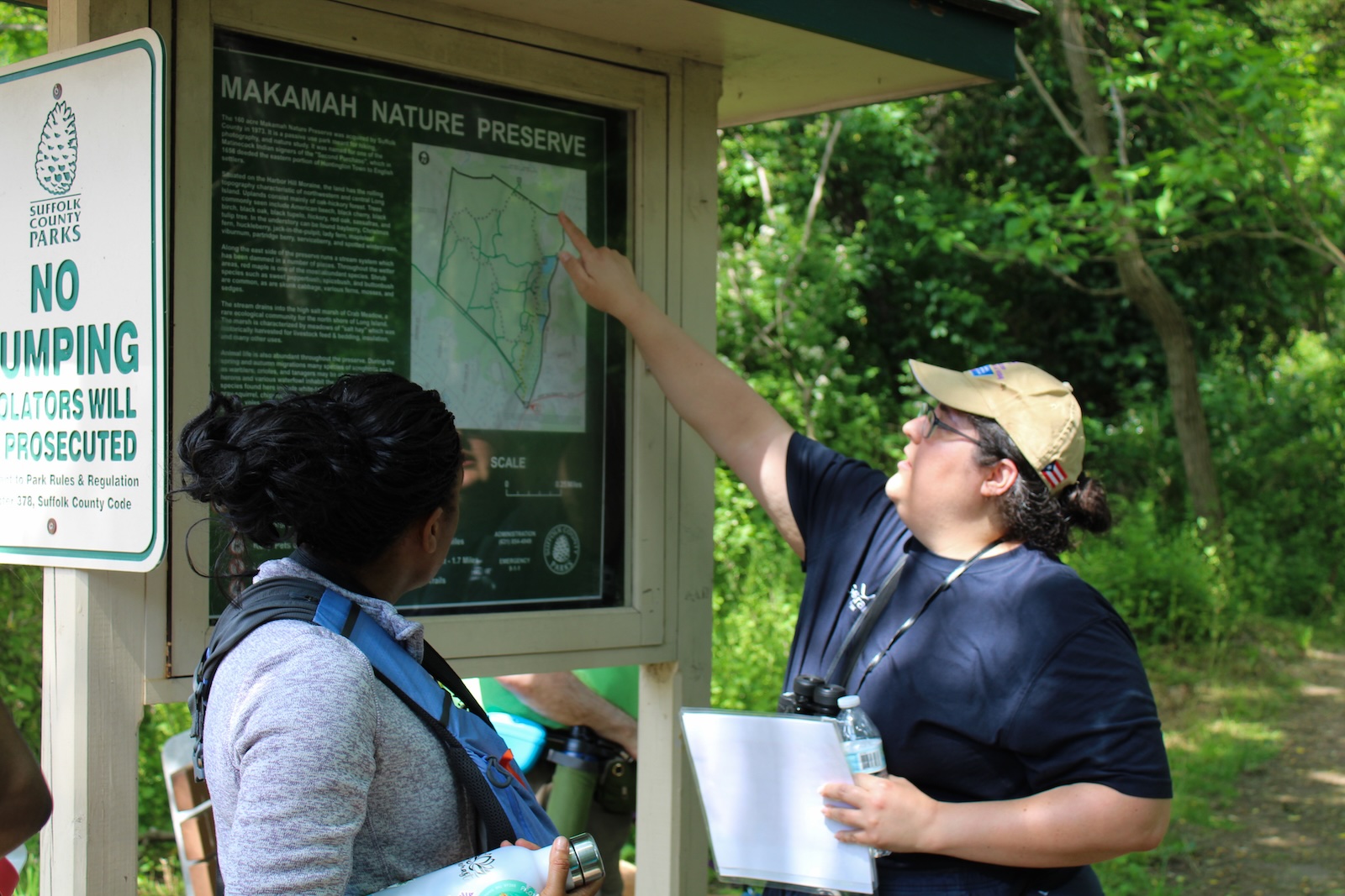 A nature walk guide pointing at a trail map.